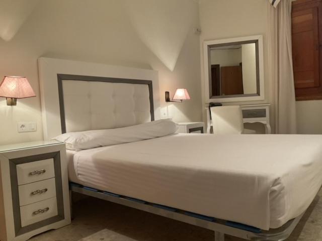 1 dormitorio con 1 cama blanca grande y espejo en Hotel el Sol, en Lanjarón