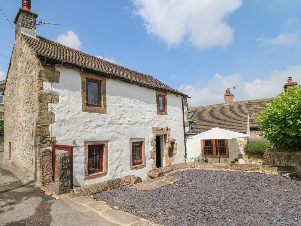 an old stone house with a driveway in front of it at Hope Cottage in Bakewell