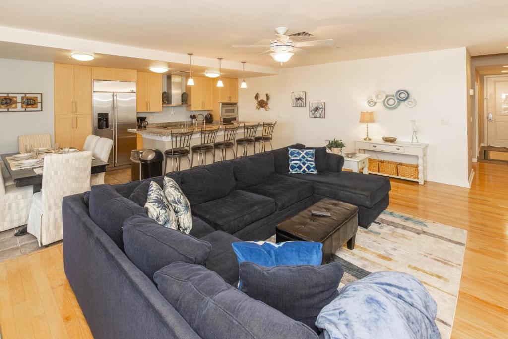 sala de estar con sofá azul y cocina en The Sanctuary - Sunset Thrille Penthouse B431, en Virginia Beach