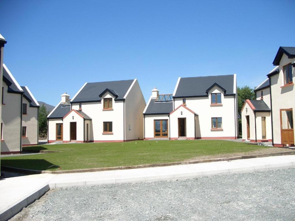 una fila de casas blancas con un patio verde en No 14 Holiday Village House, Sneem, 4 bedrooms en Sneem