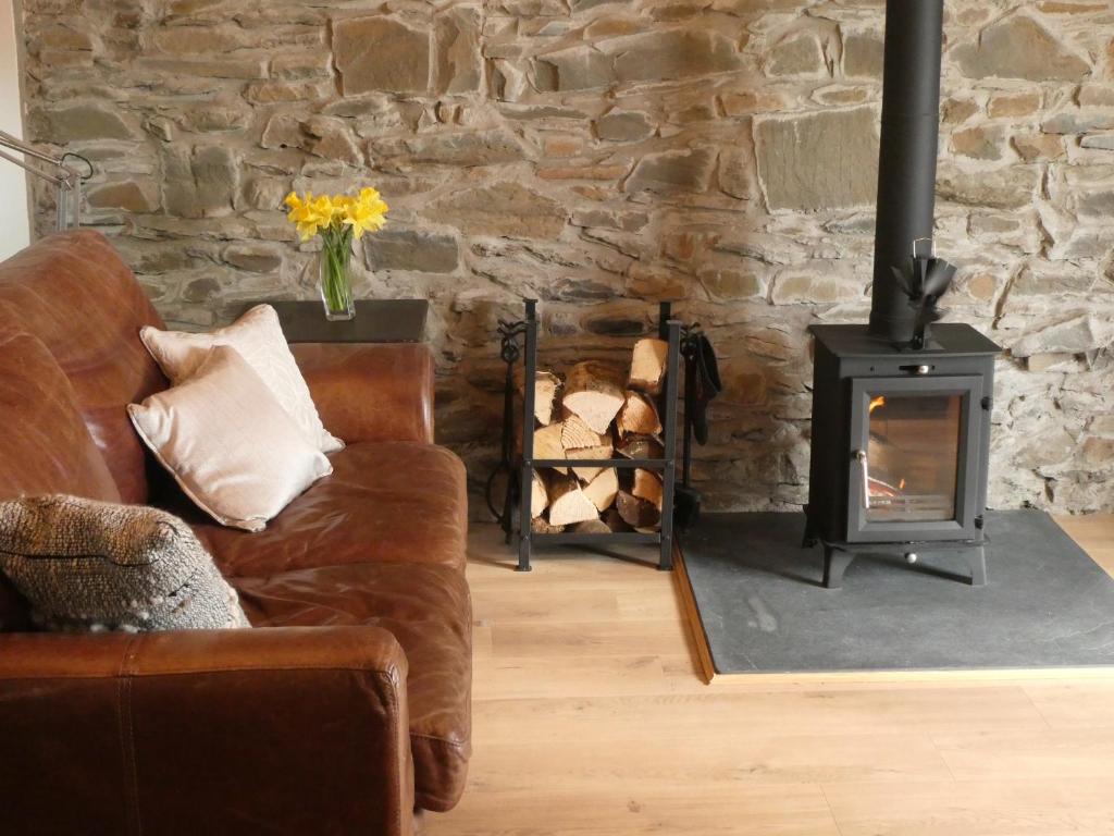 salon z kanapą i piecem opalanym drewnem w obiekcie Cheerful cottage between the mountains and the sea in West Wales w mieście Penuwch