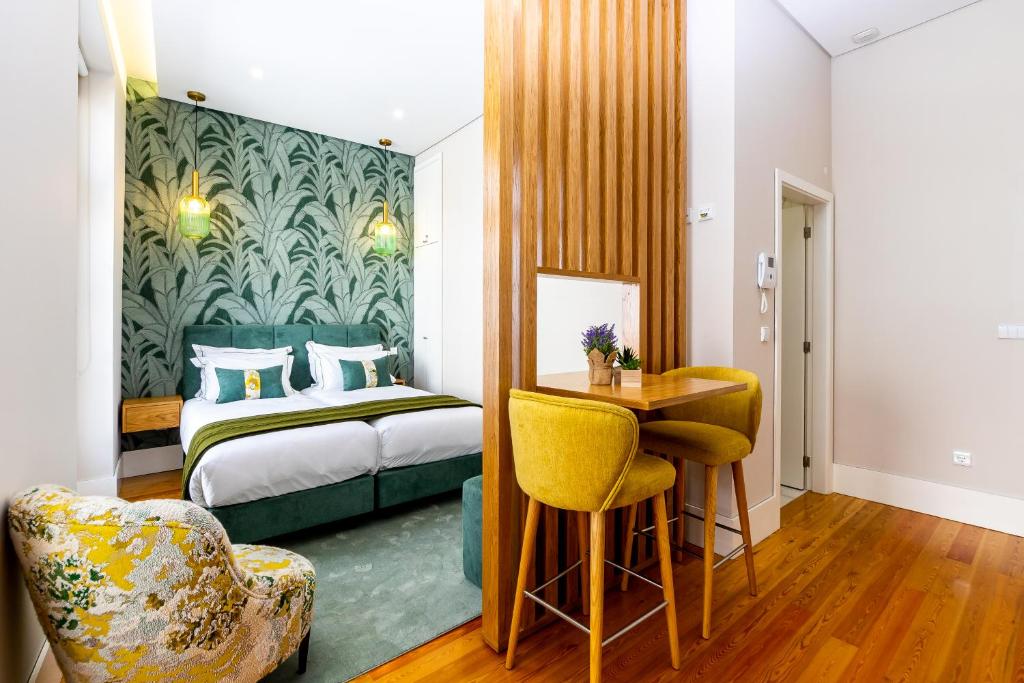 um quarto de hotel com uma cama, uma mesa e cadeiras em Mouzinho 129 - Medronheiro & Oliveira no Porto