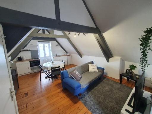 a living room with a blue couch and a table at studio centre ville 3ème étage sans ascenceur in Saint-Pol-de-Léon