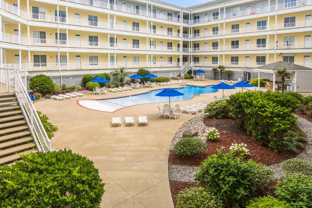 un edificio de apartamentos con piscina, sillas y sombrillas en The Sandbridge Dunes - Katz Meow 204, en Virginia Beach