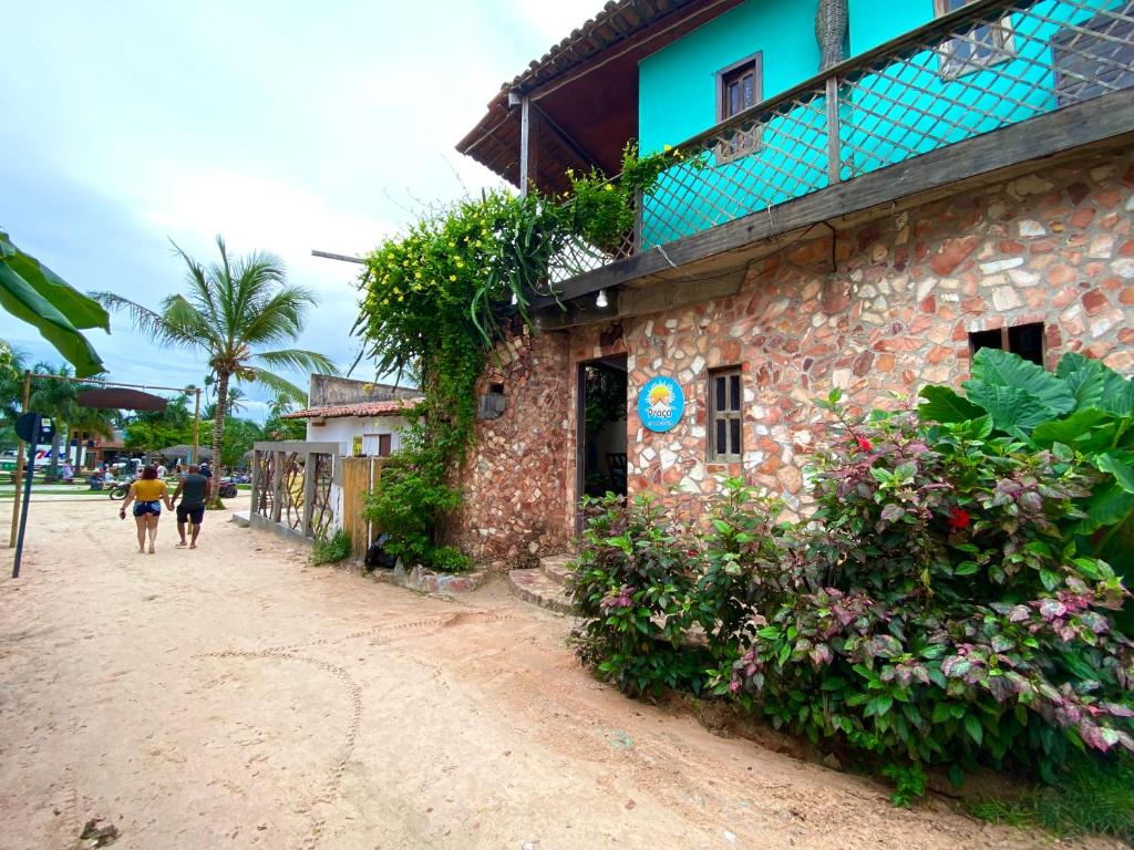 a couple of people walking down a dirt road next to a building at Pousada da praça in Jericoacoara