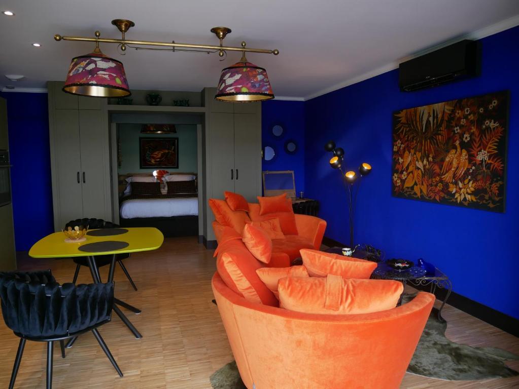 a living room with orange chairs and a blue wall at Suite 24 in Aubenas