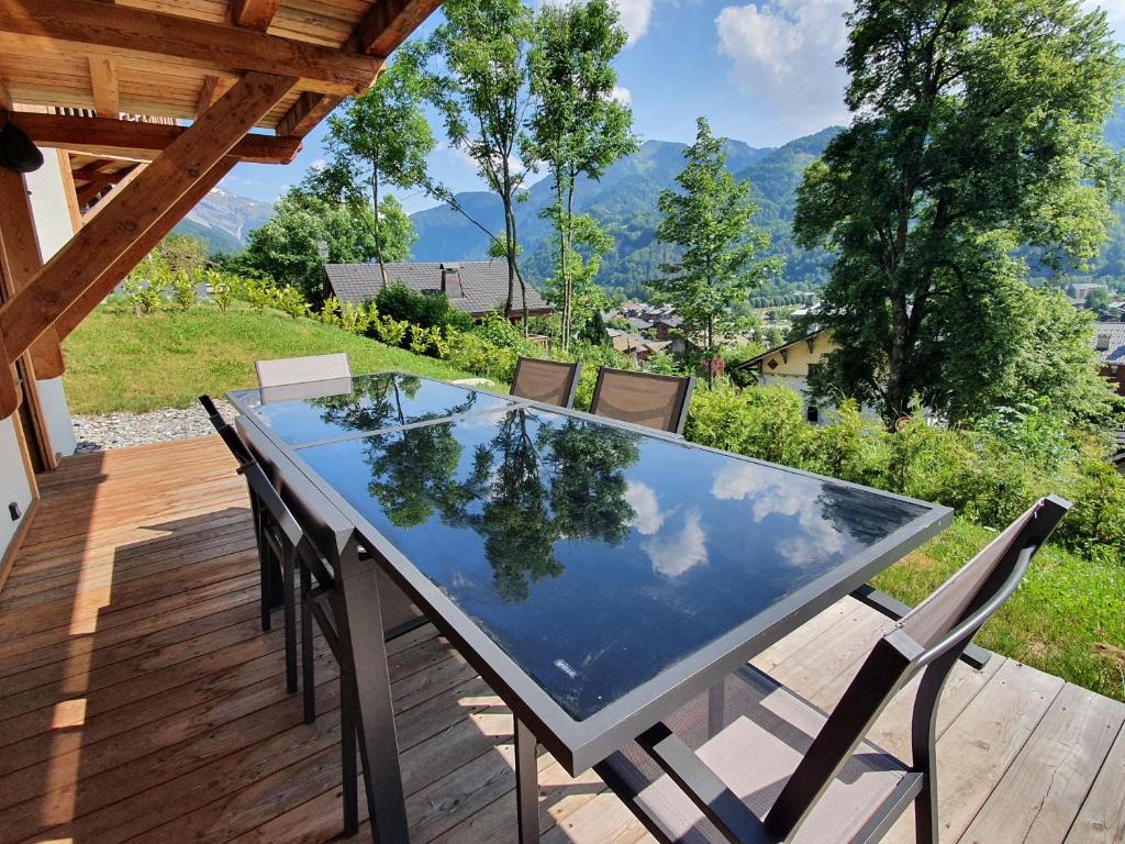 a table and chairs on a deck with a view of the mountains at Plein Soleil Modern 3 bedroom apartment with stunning mountain views in Samoëns
