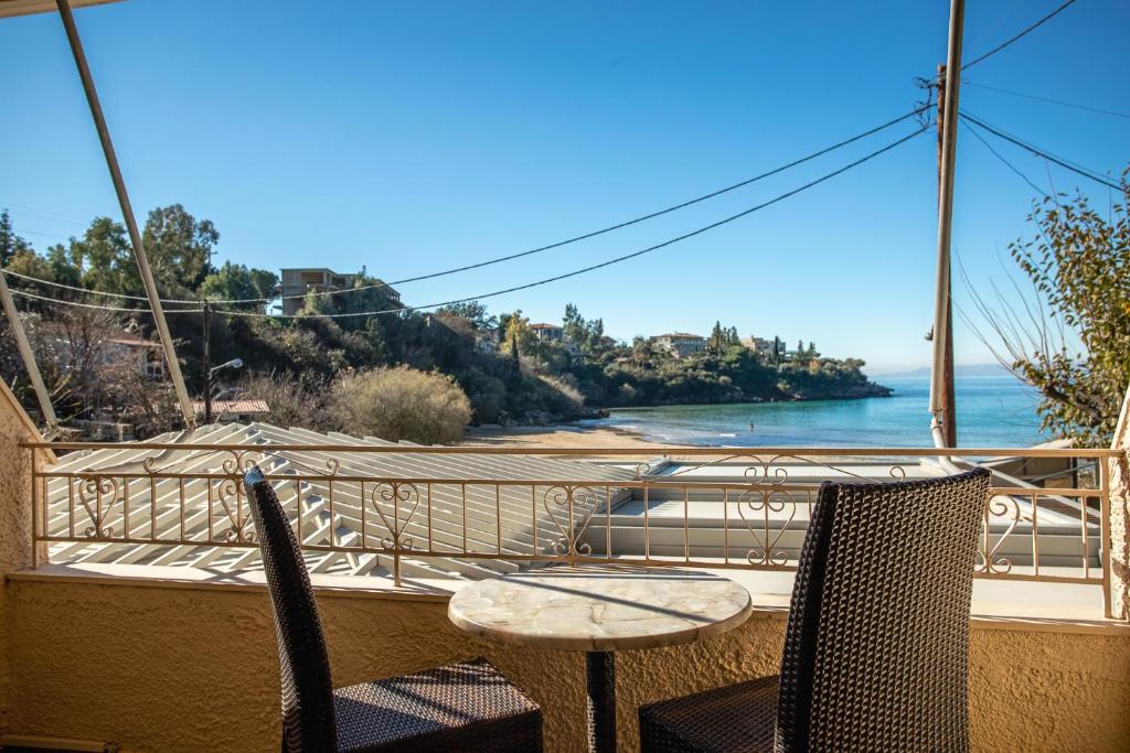 uma mesa e cadeiras numa varanda com vista para o oceano em Kalogria em Stoupa