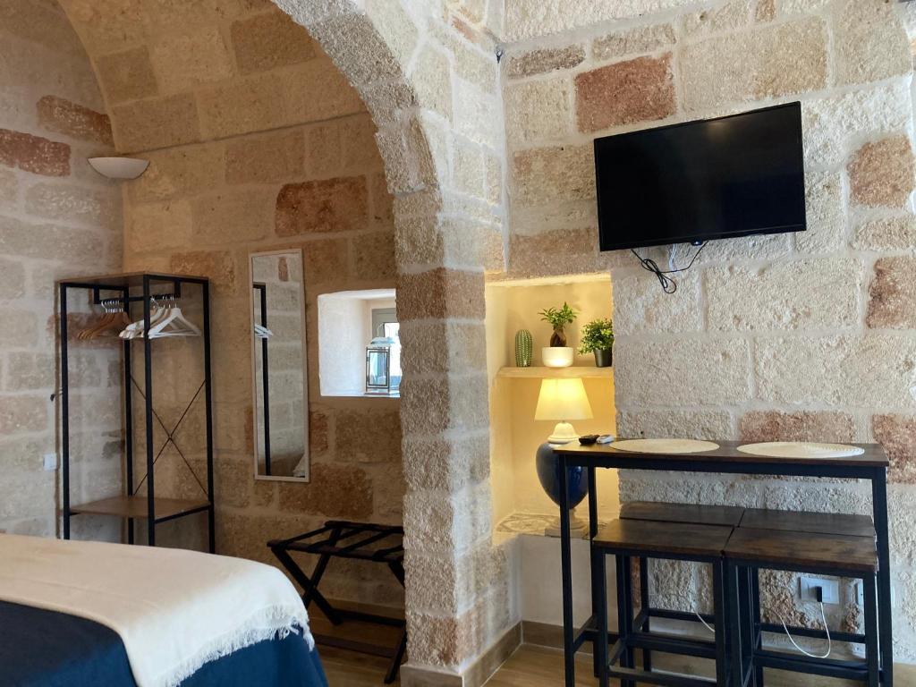 um quarto com uma cama e uma televisão numa parede de pedra em Tresor 65 em Polignano a Mare