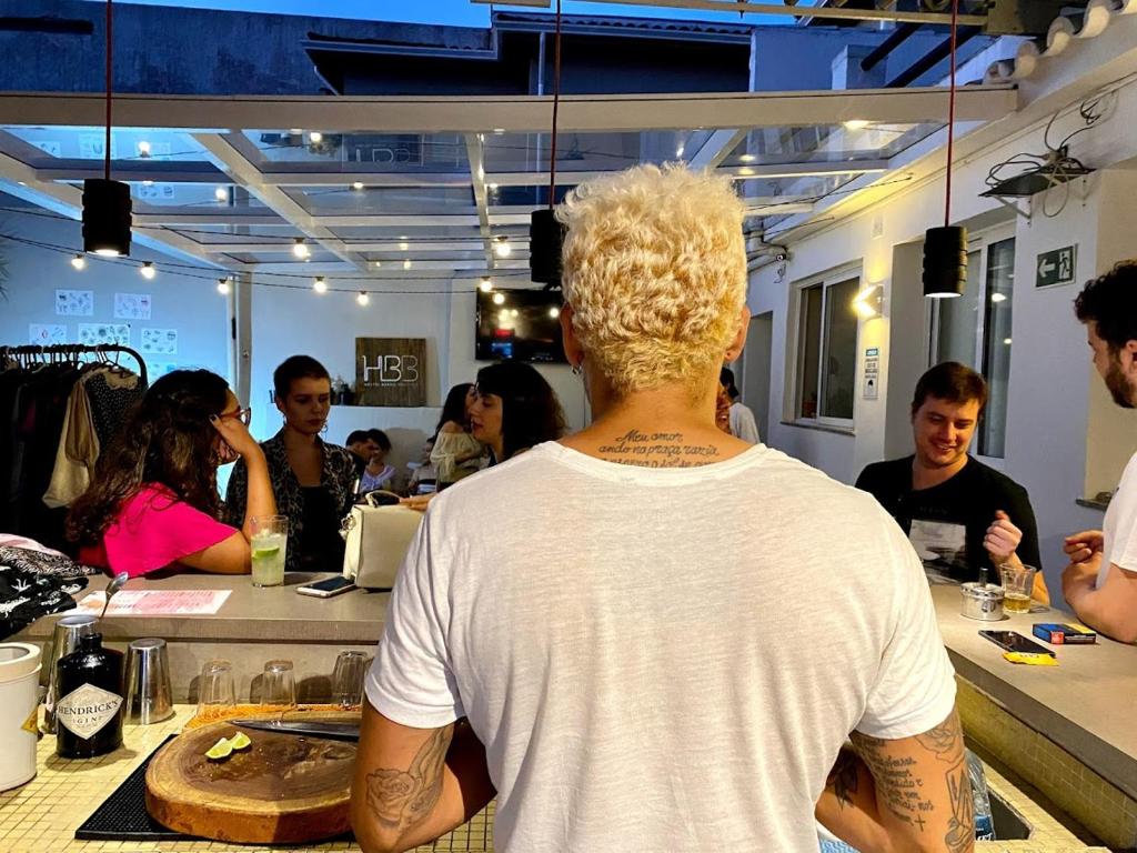 a man with tattoos on his back sitting at a bar at HBB Hostel - Vila Madalena in Sao Paulo