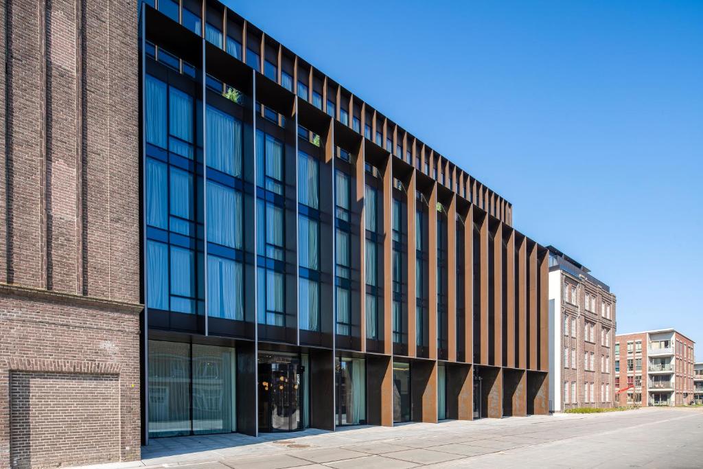 un edificio de oficinas con ventanas de cristal en una calle en NEO KVL Hotel by TASIGO en Oisterwijk