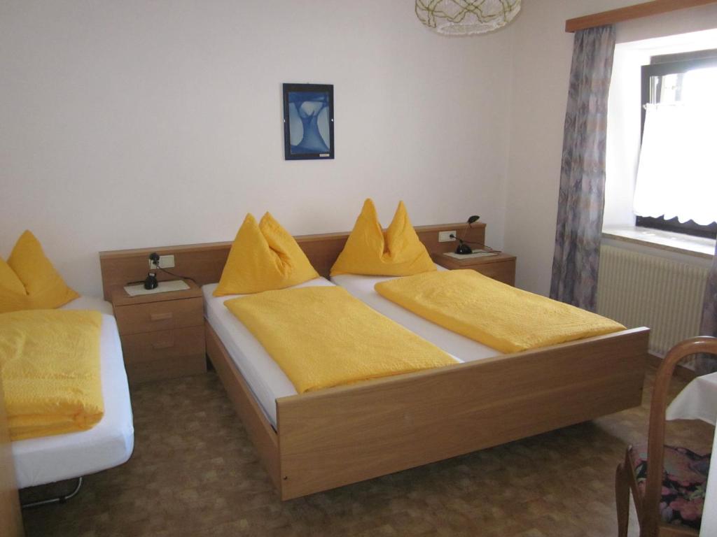 a bedroom with two beds with yellow pillows at Gasthof zum Roessl in San Genesio Atesino