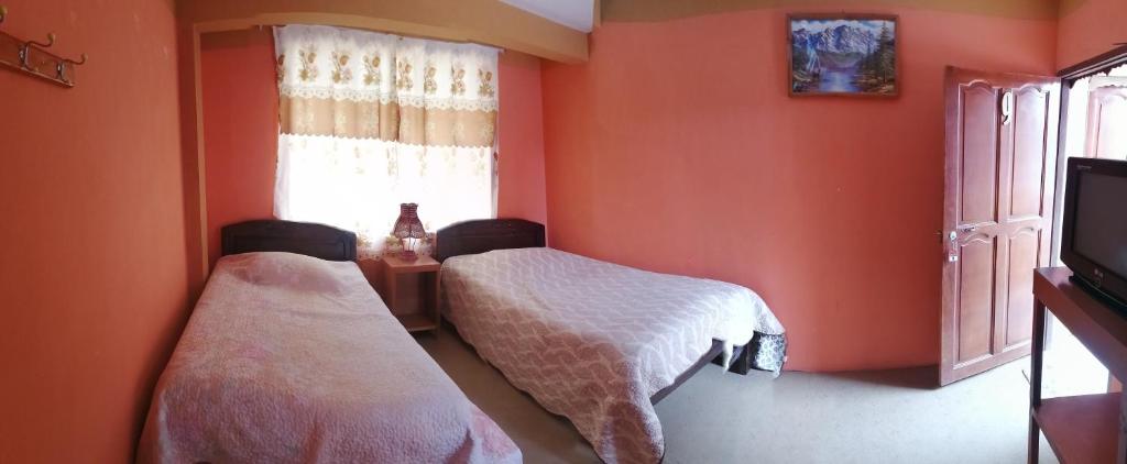 two beds in a room with orange walls at Hostal Puerto Alegre in Copacabana