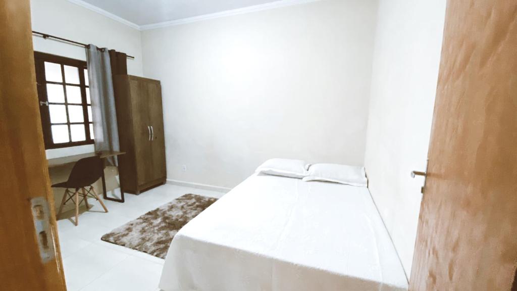 um quarto branco com uma cama e uma janela em Kitnets Dona Lucia SJC em São José dos Campos