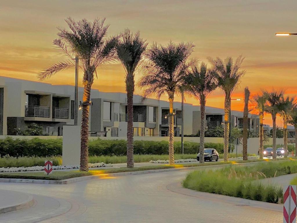 a street with palm trees in front of a building at Modern Dubai Hills Luxury 4 BEDROOM VILLA in Dubai