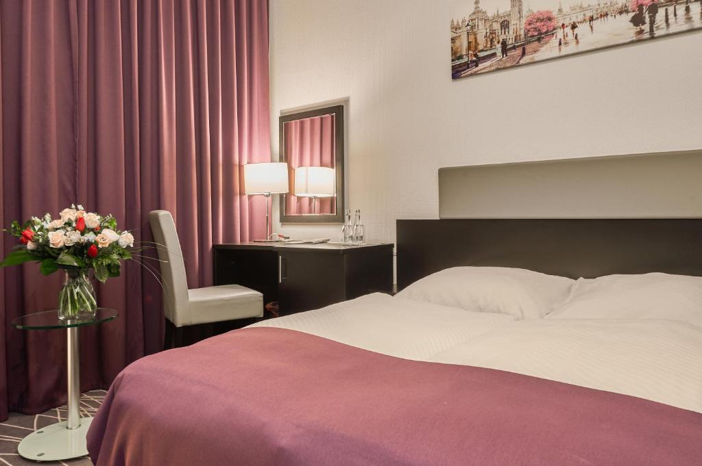 a bedroom with a bed and a desk with a vase of flowers at Sky Business Hotel in Legnica