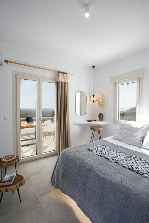 a white bedroom with a bed and a balcony at Naxos Earth Suites in Mikri Vigla
