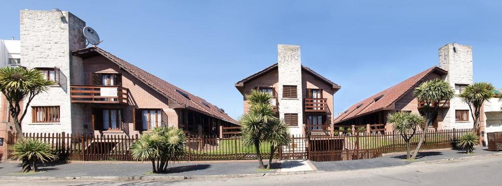 une maison avec une clôture et des palmiers devant elle dans l'établissement Complejo Tekis, à Mar del Plata