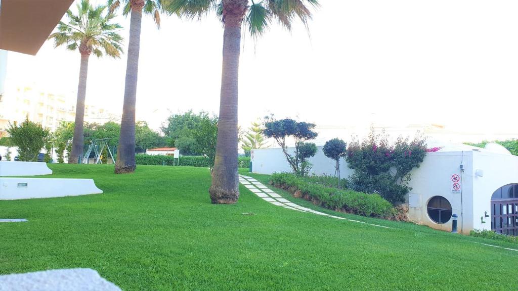 een groen park met palmbomen en een speeltuin bij Home Sweet Home in Albufeira