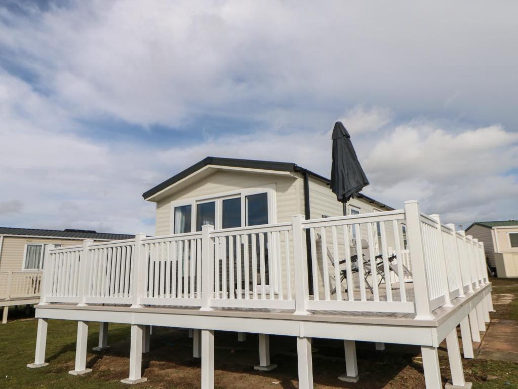une maison avec une terrasse blanche et un parasol dans l'établissement Wansbeck View 2, à Ashington
