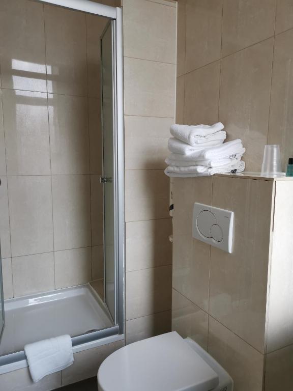 a bathroom with a shower and a toilet and towels at Hotel Albert II Oostende in Ostend