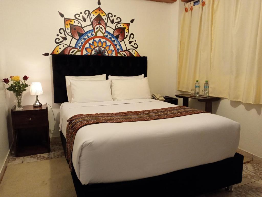 ein Schlafzimmer mit einem großen Bett mit einem dekorativen Kopfteil in der Unterkunft Inkas Land in Machu Picchu