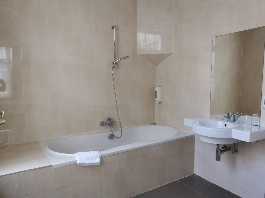 a bathroom with a bath tub and a sink at Hotel Albert II Oostende in Ostend