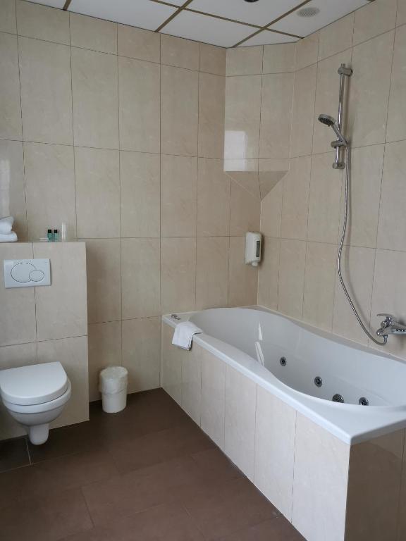a bathroom with a bath tub and a toilet at Hotel Albert II Oostende in Ostend