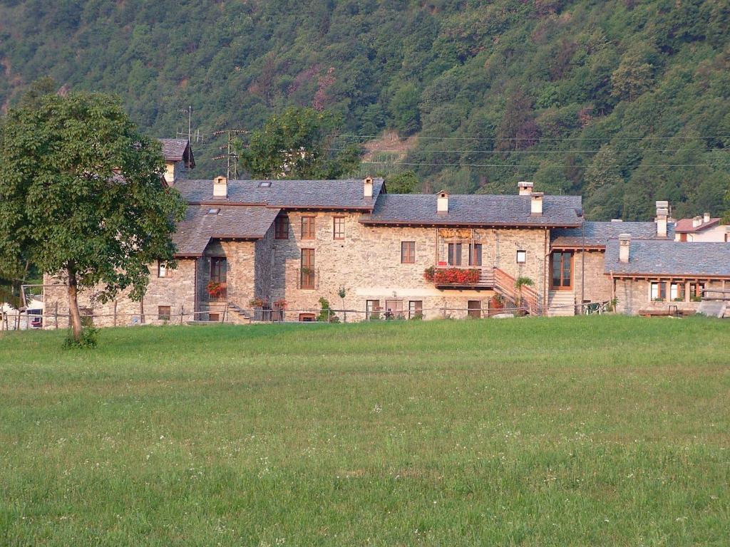 a large stone house in a field of grass at Le Case dei Baff in Morbegno