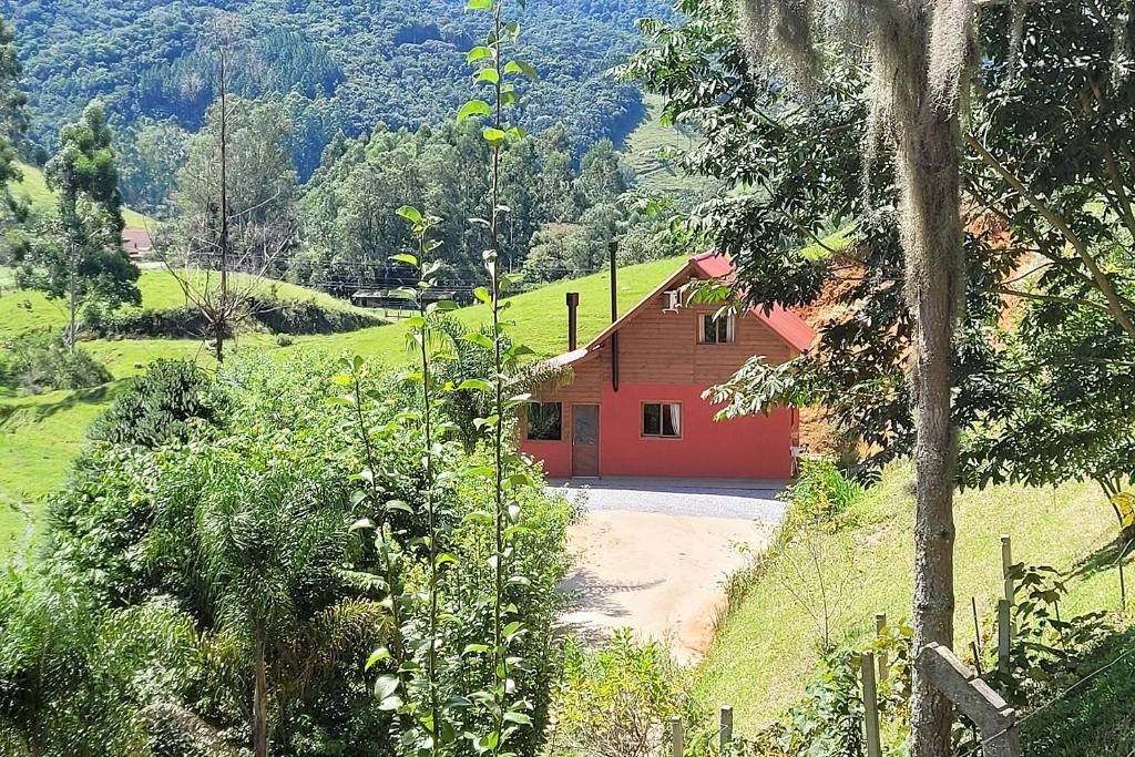 een rood huis in het midden van een veld bij Recanto dos Sabiás - Chalés São Bonifácio SC in São Bonifácio
