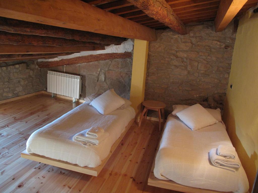 2 camas en una habitación con suelo de madera en L'Esgolfa de ca l'Ortís en Figuerosa