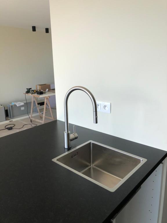a kitchen with a sink in a black counter top at Residentie Zeezicht in Eksel