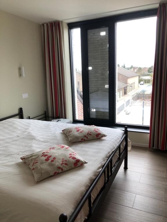 a bedroom with a bed with two pillows and a large window at Residentie Zeezicht in Eksel