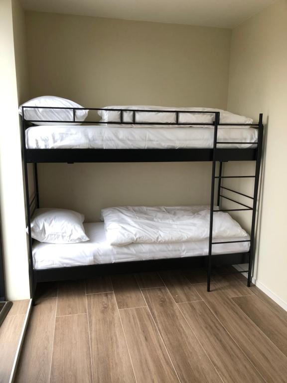 two bunk beds in a room with white sheets at Residentie Zeezicht in Eksel
