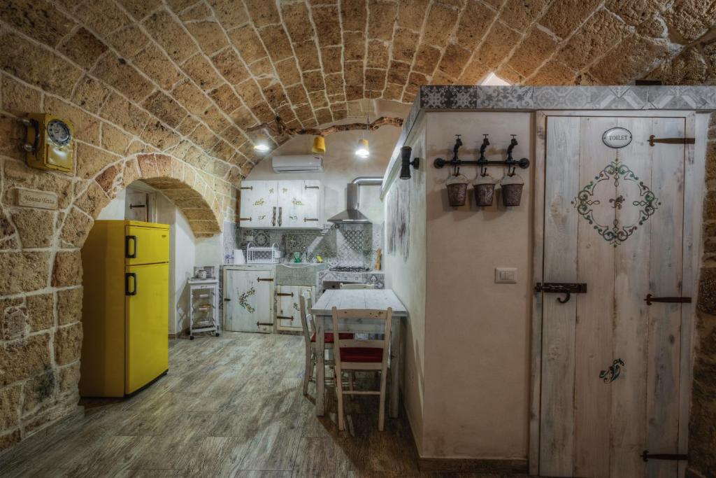 a kitchen with a yellow refrigerator and a stone wall at Le casette di Nardò in Nardò