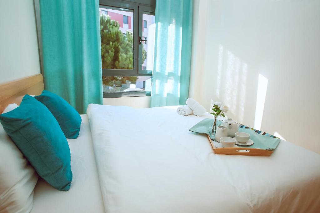 a white bed with blue pillows and a tray on it at AL34 - Apartamento a 400 metros de la playa Fenals in Lloret de Mar