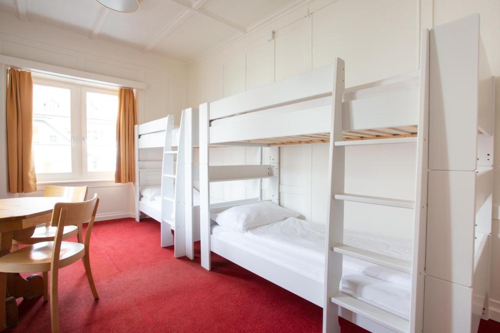 a room with two bunk beds and a table and a desk at Zunfthaus zur Rebleuten in Chur