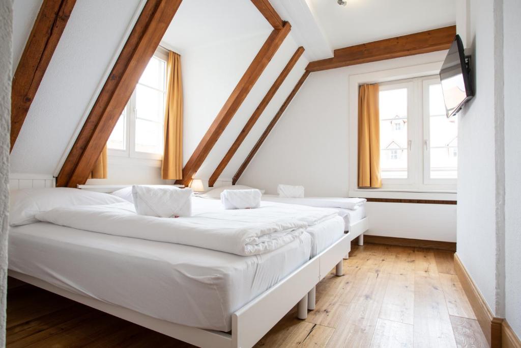 a row of beds in a room with windows at Zunfthaus zur Rebleuten in Chur