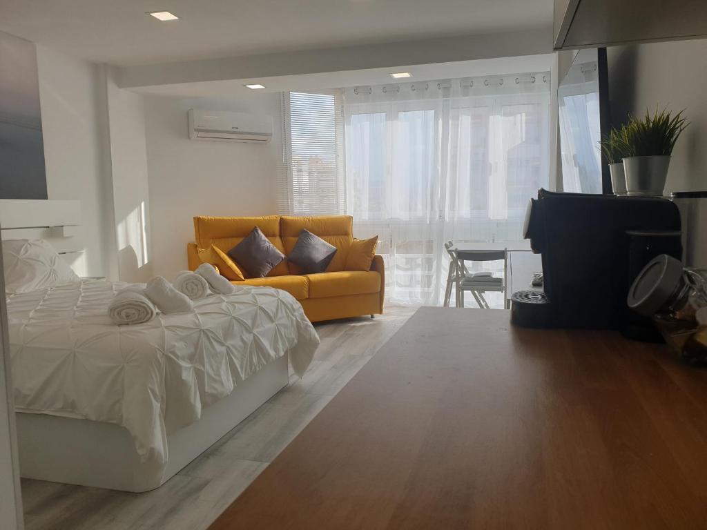 een slaapkamer met een bed en een gele bank bij Estudio Amalfi in Torre del Mar