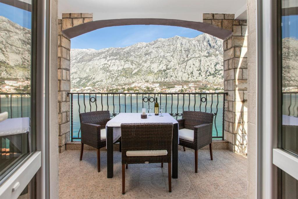 un tavolo e sedie su un balcone con vista sulle montagne di Apartments Vuković a Kotor (Cattaro)