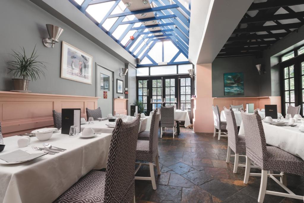 uma sala de jantar com mesas, cadeiras e janelas em Hotel Ceilidh-Donia em Edimburgo