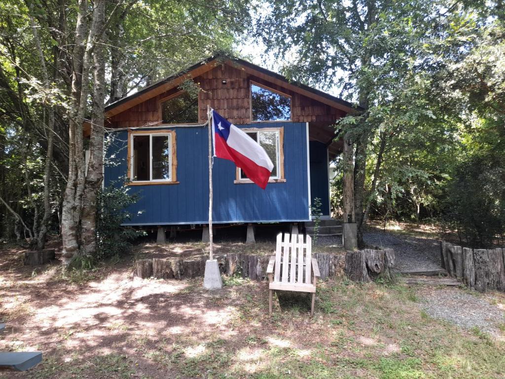una casita azul con una bandera y un banco en Cabaña Don Humbert en Riñinahue