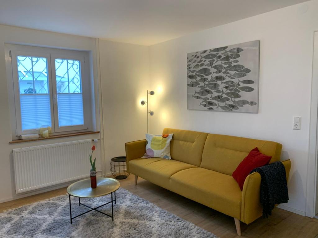 uma sala de estar com um sofá amarelo e uma mesa em Ferienwohnungen Bohner/ Wohnung Katharina em Meersburg