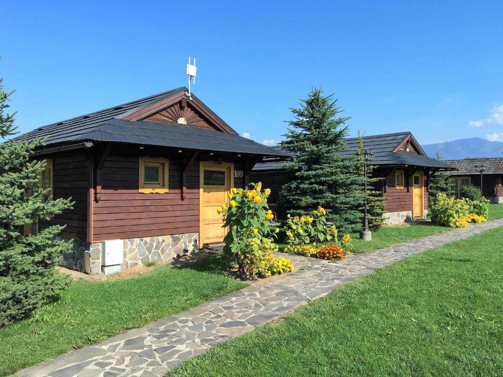 a log home with a pathway in front of it at Tatralandia Chatky in Liptovský Mikuláš