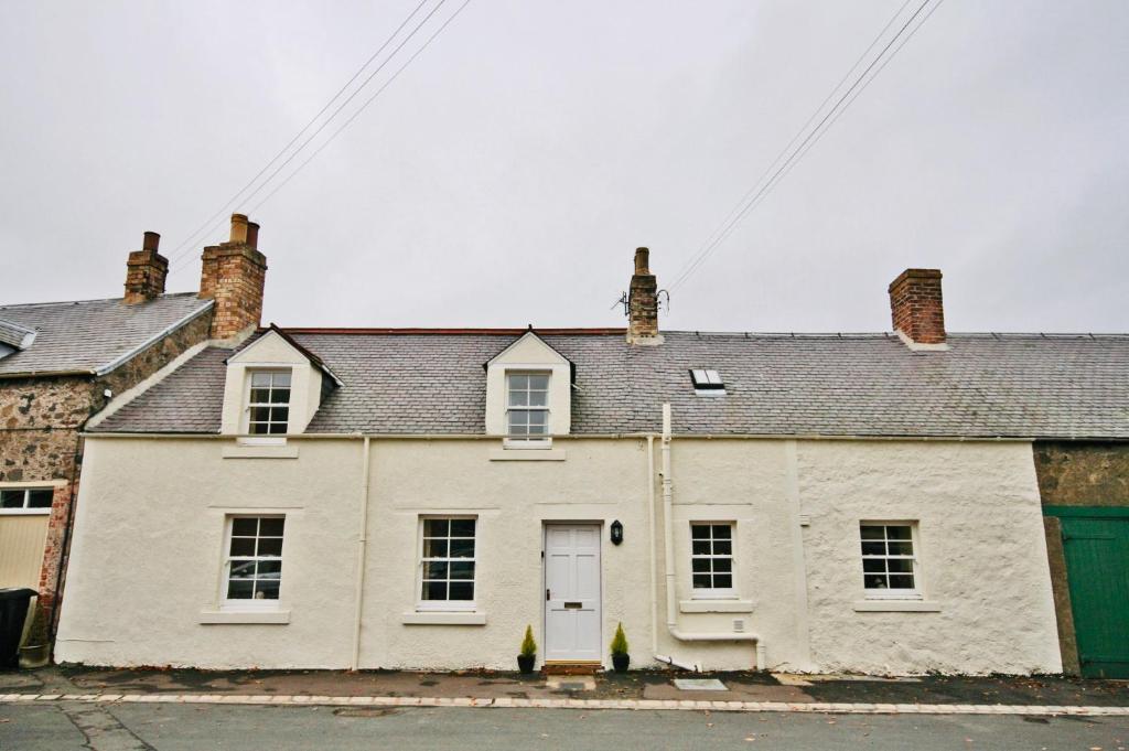 a white house with a white door and windows at The Nook, Morebattle. in Morebattle