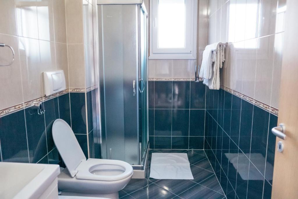 a bathroom with a toilet and a glass shower at Blue Paradise Hotel in Orikum