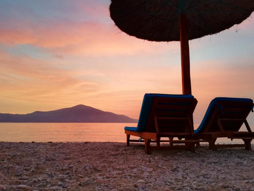 two chairs and an umbrella on a beach at Blue Paradise Hotel in Orikum