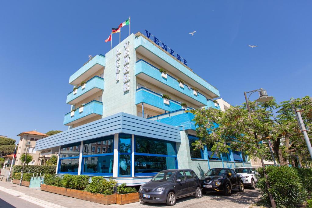 un edificio con coches estacionados frente a él en Hotel Venere en Cesenatico