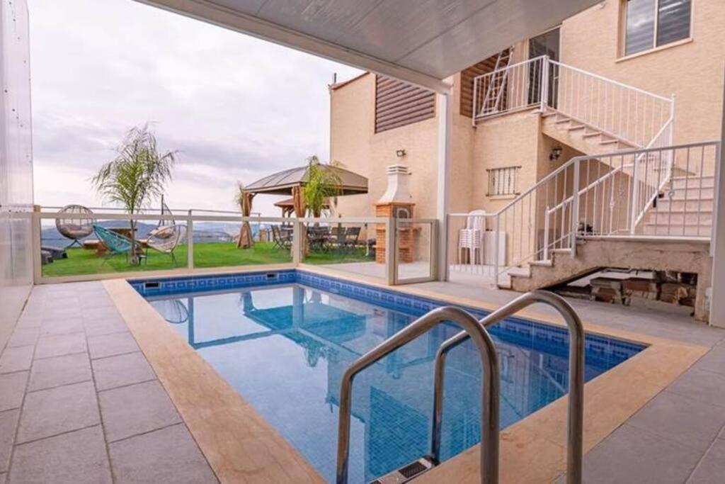 a swimming pool in front of a house at Blue lake luxury villa for families in ‘Ein el Asad