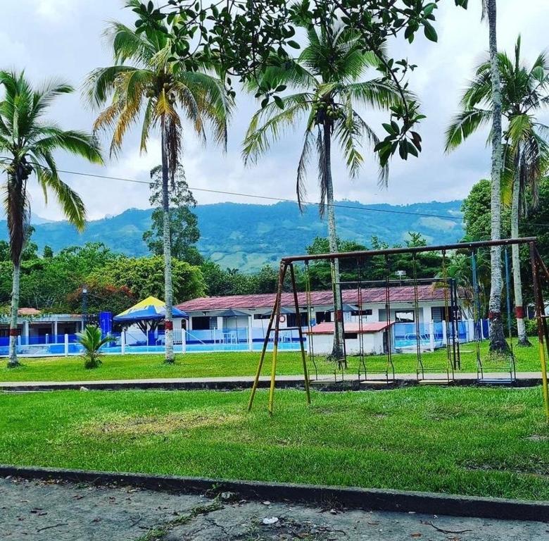 a swing set in a park with palm trees at El Palmar in Guaduas